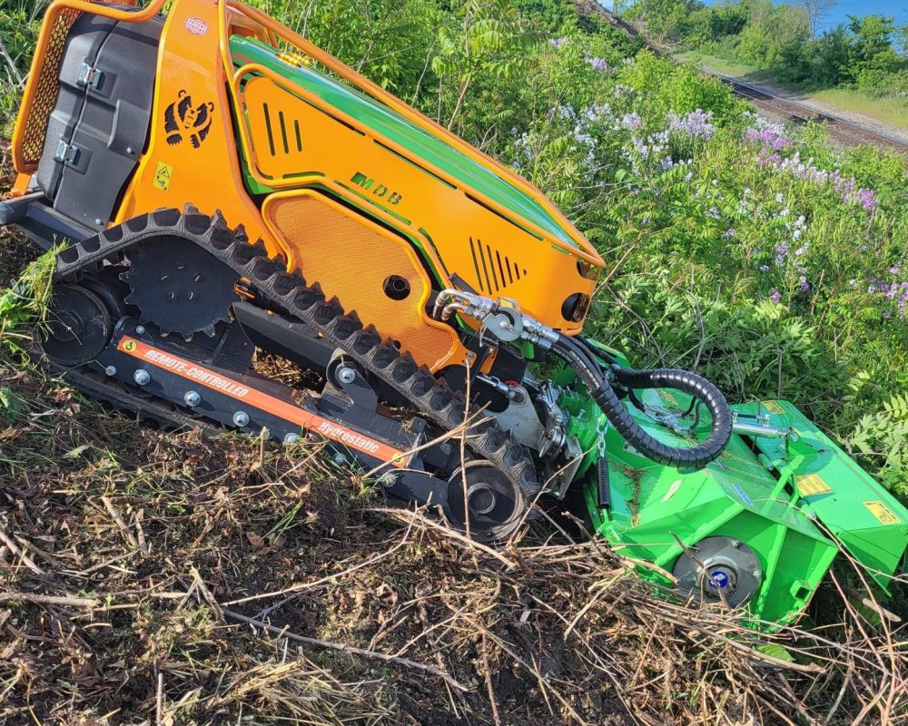 Remote-controlled Green Climber mowing heavy brush on a steep embankment in Northwest Indiana